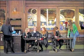  ?? Tolga Akmen / Getty Images ?? People drink at the outside tables of a cafe in central London on Thursday, the first day of new earlier closing times for bars and pubs in the U.K. to combat the spread of the coronaviru­s.