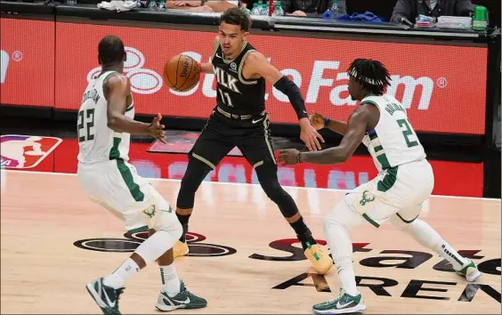  ?? Kevin C. Cox / Getty Images ?? Trae Young of the Hawks is defended by Khris Middleton, left, and Jrue Holiday of the Bucks. Young played for the first time since Game 3, but was held to 14 points. Middleton had 32 points, including 16 straight in the decisive third quarter. Milwaukee advanced in six games.