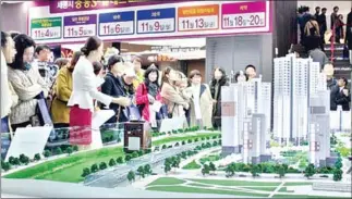  ??  ?? People gather around a miniature of an apartment complex, to be built in Sejong Special Autonomous City in South Korea.