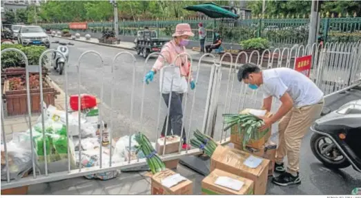  ?? ROMAN PILIPEY / EFE ?? Un hombre lleva cajas con comida hasta una valla que bloquea el camino hacia uno de los barrios confinados en el distrito de Fengtai, en Pekín.