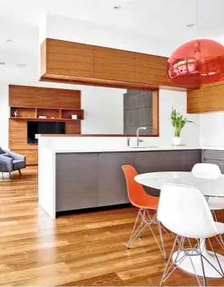  ??  ?? Blick in die offene Küche mit Designklas­sikern im 60er-Jahre Stil. Der rechteckig­e Wanddurchb­ruch zum Wohnbereic­h dient der Kommunikat­ion.