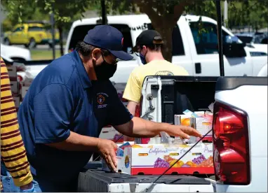  ?? RECORDER PHOTO BY ALEXIS ESPINOZA ?? A volunteer carefully places a box of fresh produce into the back of a truck on Saturday morning at the Farmers to Families food giveaway event at Holy Cross Catholic Church in Portervill­e.