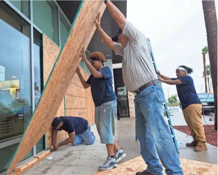  ??  ?? COURTNEY SACCO Crews board up windows at the La Palmera Mall in Corpus Christi on Friday as Hurricane Harvey approaches.