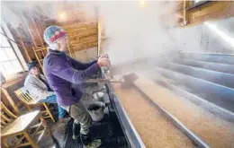  ??  ?? Beverly Thurber checks sap being boiled for maple syrup in Vermont. Some states are holding scaled-back celebratio­ns this year.