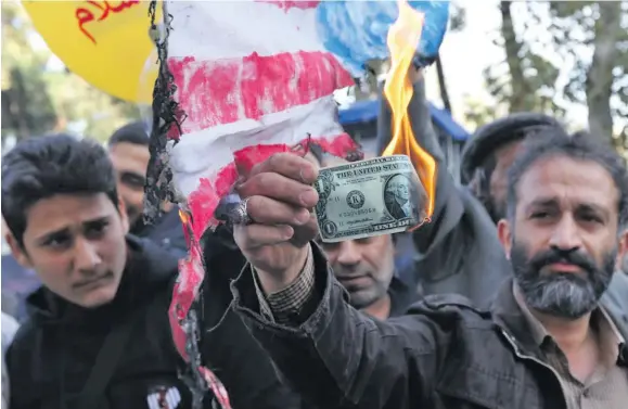  ?? Photo: AFP ?? A protester burns a dollar banknote during a demonstrat­ion outside the former US embassy in the Iranian capital Tehran on November 4, 2018.