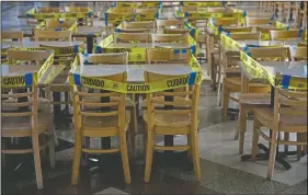  ??  ?? Caution tape is wrapped around dining tables and chairs at a food court.