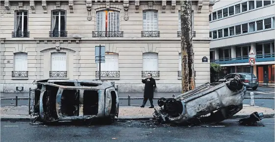  ?? THIBAULT CAMUS THE ASSOCIATED PRESS ?? A man takes a snapshot of charred cars near the Arc de Triomphe on Sunday, the day after a protest against rising taxes and the high cost of living turned into a riot in the French capital.