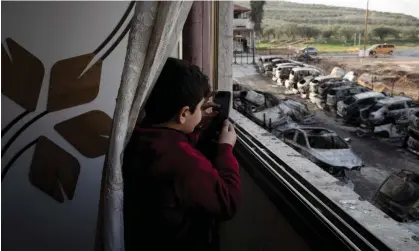  ?? ?? A Palestinia­n boy films vehicles torched in an attack by settlers in Hawara, near the West Bank city of Nablus, last year. Photograph: Maya Alleruzzo/AP