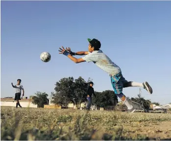  ??  ?? Gaspar Baltazar stops a shot from a teammate at soccer practice in Huron, Calif. While California may be famous for its glamour and wealth, the Central Valley has struggled to offer good jobs and positive distractio­ns for kids.