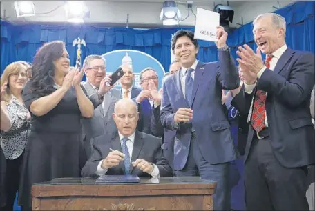  ?? Rich Pedroncell­i Associated Press ?? STATE SEN. Kevin de León holds up the environmen­tal measure he wrote after it was signed into law by Gov. Jerry Brown on Monday in Sacramento. The law will take effect in January, with California pledging to eliminate fossil fuels from its electric grids by 2045.