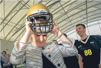  ??  ?? Nicola Sturgeon tries on an American football helmet at yesterday’s opening.