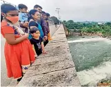 ?? — P. SURENDRA ?? Visitors enjoy the sight of water gushing out from two gates of Himayatsag­ar reservoir on Tuesday. After many years, the gates have been opened twice during this monsoon.