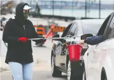  ?? DAN JANISSE ?? CUPE member Cassandra Gawne uses a multi-use grabber and bucket to collect money during the annual Goodfellow­s newspaper drive that adopted new safety protocols this year because of COVID-19.