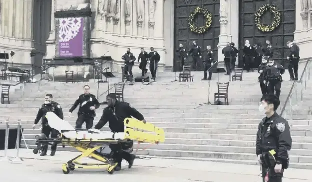  ??  ?? 0 Emergency medical personnel in the aftermath of the shooting at the end of a Christmas choral concert on the steps of the Manhattan cathedral