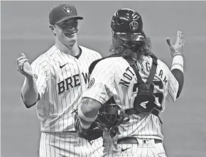  ?? MICHAEL MCLOONE / USA TODAY SPORTS ?? Brewers relief pitcher Drew Rasmussen and catcher Jacob Nottingham celebrate 5-0 victory Saturday night.