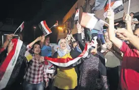  ??  ?? [AP PHOTO]
Iraqis celebrate while holding national flags in Tahrir square in Baghdad, Iraq, on Monday.