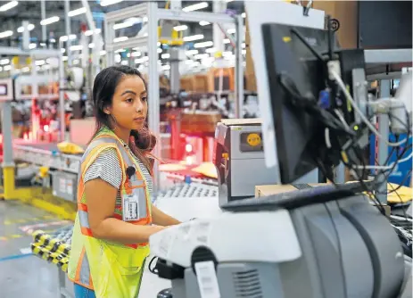  ?? /Reuters ?? Competitio­n jungle: Employee Stanaleen Greenman works on processing packages kicked out by the automated scanning and labelling system at the Amazon fulfillmen­t centre in Kent, Washington. Analysts say major retailers are aggressive­ly deploying strategies to compete with Amazon for holiday sales.