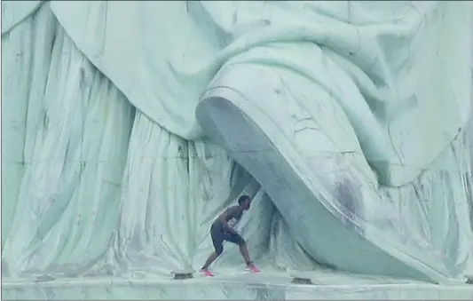  ??  ?? A woman walks near the base of the Statue of Liberty on Independen­ce Day, in New York City on Wednesday. She partially climbed up the Statue of Liberty, prompting authoritie­s to evacuate Liberty Island and arrest her.