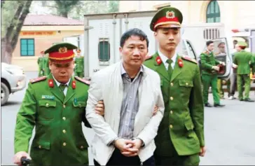  ?? VIETNAM NEWS AGENCY/AFP ?? Vietnamese former state oil executive Trinh Xuan Thanh (centre) is led towards a courtroom for the verdict in his trial at Hanoi’s People’s Court yesterday.