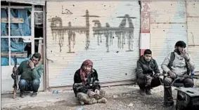  ?? FELIPE DANA/AP ?? U.S.-backed fighters of the Syrian Democratic Forces sit outside a building Saturday in Baghouz, Syria. The SDF says the end to the extremist group ISIS will happen soon.