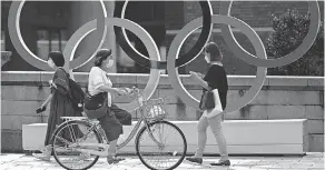  ?? HIRO KOMAE/ AP ?? People walk past the Olympic rings installed near the Nippon Bashi bridge in Tokyo.