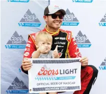  ??  ?? Kyle Larson and his son Owen kneel behind the pole flag after qualifying for the NASCAR Sprint Cup series auto race in Brooklyn, Michigan, on Friday. (AP)