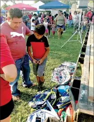  ?? SALLY CARROLL/MCDONALD COUNTY PRESS ?? Jose Hernandez-Lopez (left) guides his son, Josque, while he tries to find the perfect backpack. Several lucky winners were able to pick out a backpack at the Noel First Friday/Back-To-School event. The Noel Betterment Associatio­n teamed up with the Noel Elementary and Primary schools to host the event, which drew a huge crowd to enjoy games, music, a free waterslide, treats and more.