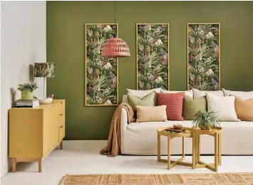  ?? ?? Innovative use of wallpaper, with complement­ary paint colours, makes this room feel like a jungle oasis. The rear wall is painted in Resene Woodland with panels in Resene Wallpaper Collection 91210. Side wall and floor painted in Resene Blanc, sideboard and panel frames in Resene Teak, coffee tables in Resene Papier Mache and the light fitting is Resene Crail. On the sideboard, the planter is Resene Avocado, the rope-handled bowl is Resene Colorwood Be Easy and the lamp base is Resene Tea. On the table, the painted book is Resene Yogi and the tealight holder is Resene Brown Sugar. Sofa from Nood, rug from Mocka, throws and leaf cushion from Adairs, rust cushion from Freedom. Project by Vanessa Nouwens, imaGe by Bryce Carleton