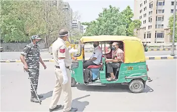  ?? — AFP photo ?? Police personnel stop vehicles at a checkpoint during a weekend lockdown imposed by the government amidst rising Covid-19 coronaviru­s cases, in New Delhi.