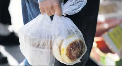  ?? ERIC RISBERG/THE ASSOCIATED PRESS ?? A man carries food in plastic bags through Chinatown in San Francisco, in this Sept. 20, 2016 photo. California voters are considerin­g a November referendum that would uphold or overturn a statewide ban on single-use plastic bags, and another ballot...