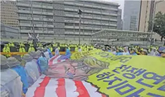  ??  ?? SEOUL: Protesters carry a banner showing illustrati­ons of US President Donald Trump as they march in front of the US Embassy after a rally demanding peace on the Korean peninsula in Seoul yesterday.—AP