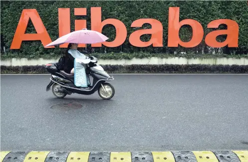  ?? AP FOTO ?? BIGGEST SHARE OFFERING.
A woman rides a bike past the company logo outside the Alibaba Group headquarte­rs in Hangzhou, in eastern China’s Zhejiang province.