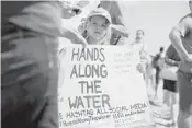  ?? JENNIFER LETT/STAFF PHOTOGRAPH­ER ?? About a hundred people held hands for 15 minutes of silence during a demonstrat­ion on Fort Lauderdale beach.