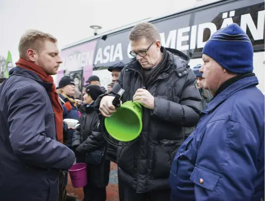  ?? FOTO: LEHTIKUVA/MINNA RAITAVUO ?? Inget val utan gratis hink. Vanhanen signerar en hink åt Mika Peuhkurine­n (till höger) vid sin kampanjbus­s under Centerns fullmäktig­e i Joensuu.■