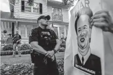  ?? Nathan Howard/Getty Images ?? A Montgomery County police officer stands guard as protesters march past Supreme Court Justice Brett Kavanaugh’s home.
