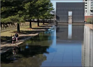  ?? The Associated Press ?? REFLECTING POOL: Visitors walk next to the reflecting pool on March 18 at the Oklahoma City National Memorial and Museum in Oklahoma City. The Oklahoma City National Memorial and Museum has announced that it will offer a recorded, one-hour television program in place of a live ceremony to mark the 25th anniversar­y of the Oklahoma City bombing due to concerns about the spread of the coronaviru­s.