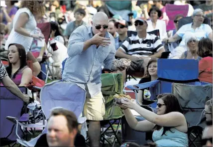  ?? PHOTOS BY MARK WEBER/THE COMMERCIAL APPEAL ?? Julian Gibbons can’t wait to dig into an order of barbecue nachos during singer Todd Snider’s “What the Folk?” Fest at the Levitt Shell. Fans who attend the free evening concerts at the Shell pack gourmet picnics, grab boxes of takeout food and bring...