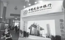  ?? A QING / FOR CHINA DAILY ?? Above left: A visitor walks past the booth of the Export-Import Bank of China during an internatio­nal financial exhibition in Beijing.