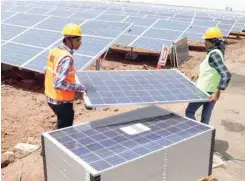  ?? — Reuters ?? Workers carry solar panels for installati­on at a solar park in Gujarat, India.