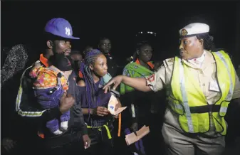  ?? Sunday Alamba / Associated Press ?? An immigratio­n officer (right) speaks to Nigerian returnees from Libya upon arrival at the airport in Lagos. Nigeria has the highest number of illegal and legal immigrants in Libya.
