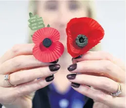  ??  ?? A Royal British Legion employee holds a present day poppy next to a poppy believed to date back to before World War II, after a box of the poppies were found in an old suitcase in Cardiff