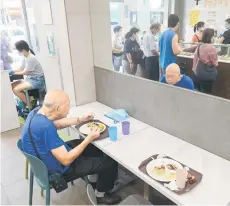  ?? ?? A diner eating a low-priced meal as customers are seen in a mirror being served two-dish mealboxes.