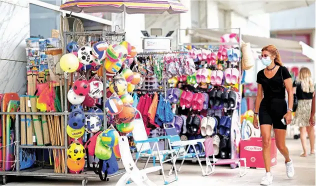  ?? Reuters ?? ↑
A woman, wearing a facemask, walks past a shop in La Baule, France, on Friday.