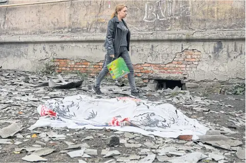  ?? REUTERS ?? A resident walks past a shelling victim near a damaged block of flats in Makiivka, Russian-controlled Ukraine on Nov 4.