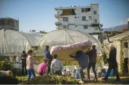  ?? FRANCISCO SECO/AP ?? Local residents carry a mattress Thursday to a greenhouse in Samandag, Turkey. People are using the structure as shelter after the massive Feb. 6 earthquake.