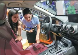  ?? WANG ZHUANGFEI / CHINA DAILY ?? A salesperso­n shows a visitor a vehicle interior at Auto China 2018 in Beijing.