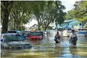  ?? AFP ?? People walk past cars partially submerged in floodwater­s in Shah Alam, Malaysia on Tuesday. —