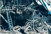  ?? EVGENIY MALOLETKA/ASSOCIATED PRESS ?? A rescue worker and police officer inspect the site of a destroyed house Saturday after a Russian attack in a residentia­l neighborho­od of downtown Kharkiv, in eastern Ukraine.