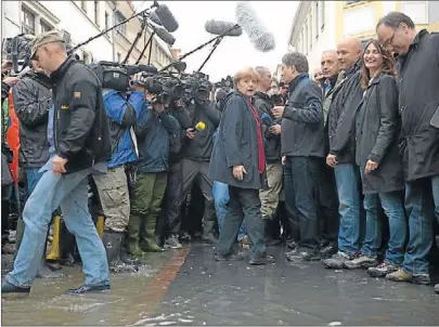  ??  ?? Angela Merkel im Gespräch mit Helfern, Betroffene­n und Reportern im überflutet­en Pirna.