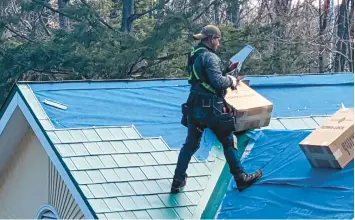  ?? TIM CARTER ?? Metal roofing is installed on a house, with each shingle made from painted aluminum.